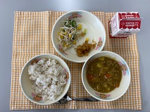 テーブルクロスに並べられた麦ごはん・牛乳・米粉のカレーライス・切り干しだいこんのサラダ・福神漬・ごまドレッシングの写真