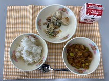 テーブルクロスに並べられたごはん・牛乳・マーボーだいこん・おから入りしゅうまい・ボイルもやし・パックしょうゆの写真