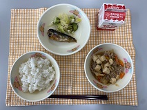 テーブルクロスに並べられたごはん・牛乳・肉どうふ・いわしのうめ煮・しんこあえの写真