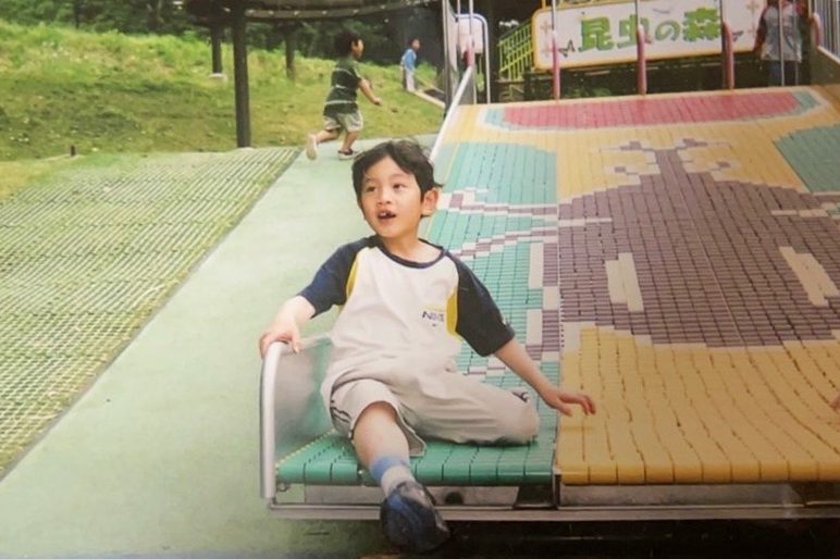昆虫のイラストがデザインされた滑り台のような所に座っている子供の写真