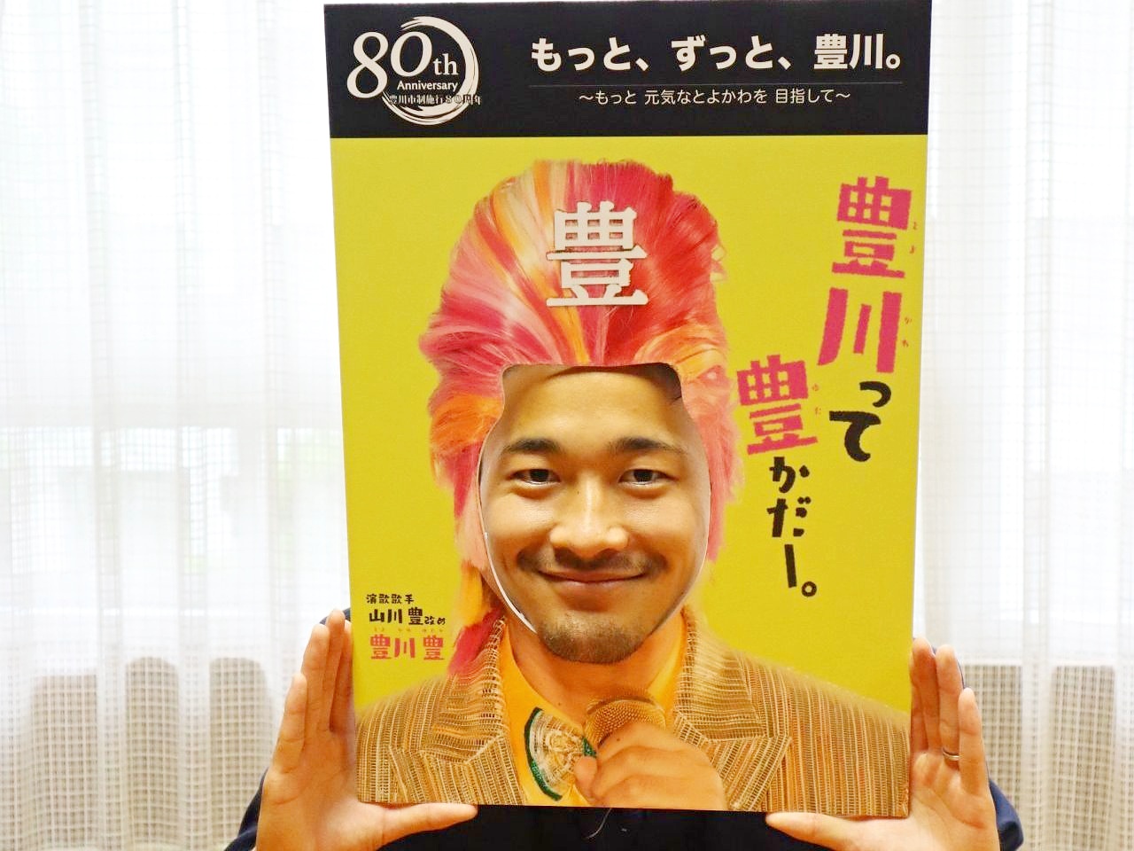 男性が「豊川って豊かだー。」と書かれた豊川豊の顔パネルに顔をはめている写真