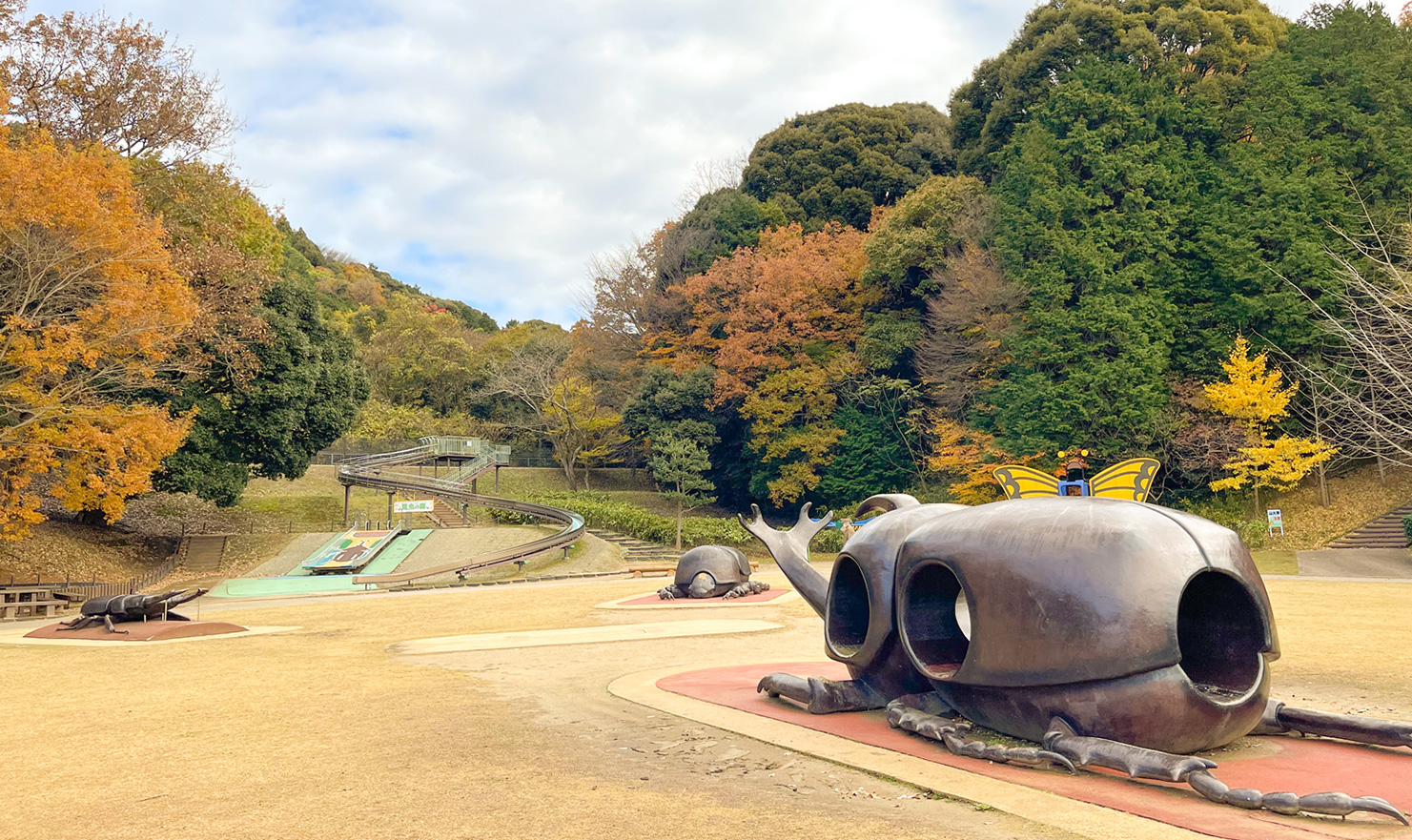 手前にオブジェがあり、奥に長い滑り台が設置されている公園の写真