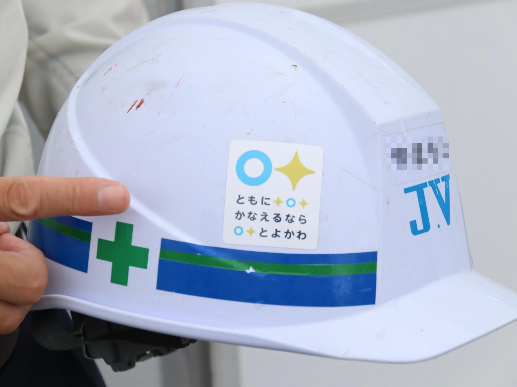 工事現場で使うヘルメットにロゴのシールを貼っている