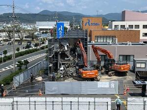 2機のオレンジ色のクレーン車を使って訓練棟が解体されている様子の写真