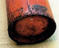 赤い消火器の底や下部金属が層状に黒く腐食している写真
