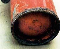 赤い消火器の底の溶接部周辺が黒く腐食している写真