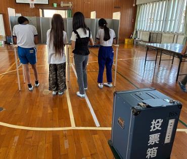 一宮西部小学校の6年生が、記載台で投票用紙に候補者を記入している様子です。