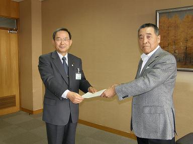屋内で2人の男性が1枚の紙を受け渡ししている写真