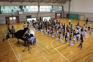 児童たちが立ち上がり演奏を聴いている写真