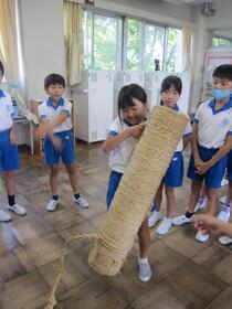 手筒と同じくらいの背丈の児童が手筒を持ち上げている写真