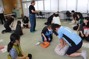 職員たちが訓練器具で心肺蘇生トレーニングを行う写真