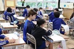 教室の席に座って勉強する青いジャージ姿の児童たちの写真