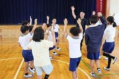 体育館で円になっている子供たちが手を上げながら中央に向かっている写真