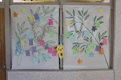 学校の掲示板に七夕の笹がプリントされた用紙があり、その上に短冊が貼られている写真