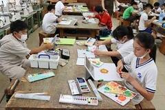 作業用のテーブルで子供たちが絵具を使ってそれぞれ絵を描いている写真