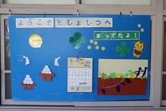 窓に「ようこそとしょしつへ まってたよ!」のタイトルテキストと共に十五夜や「大きなかぶ」をモチーフにしたイラストなどが飾られている写真
