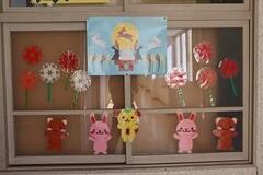 窓にうさぎやクマや花のイラストが切り抜かれた紙が貼られている写真