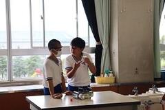 児童2人が机に置かれたガスコンロの前で立っている写真