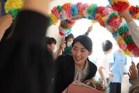 退任される先生が花のアーチをくぐって退場している写真