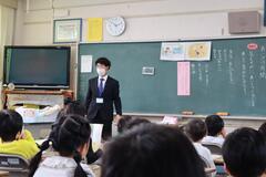 黒板の前で道徳の授業をしている先生の写真