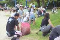 一杯になったごみ袋の周りで複数の大人や児童が草取りに励んでいる写真