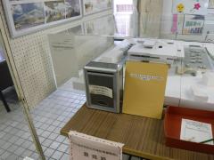 建物の模型が入ったケースにグレーの箱や黄色いボードが立てかけられている写真