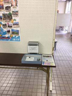 白いパーテーションと隣接して設置されている机に記入用紙やペンが置かれている写真