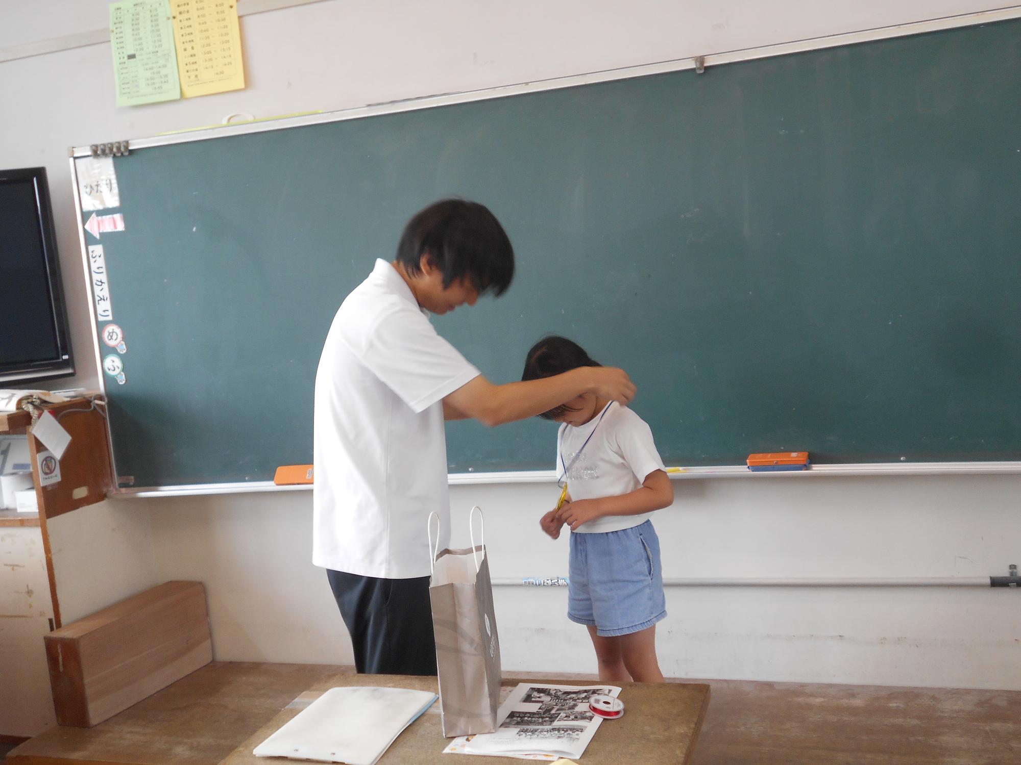 担任の先生がメダルを渡しています。