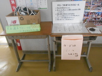 机の上にグローブの入った箱が置かれ、その隣にグローブについてのルールの記載と予約カードの記入場所がある様子の写真