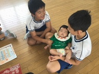 寝ている赤ちゃんを抱いてみている4年生の写真