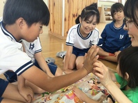 赤ちゃんとハイタッチをしている児童の写真