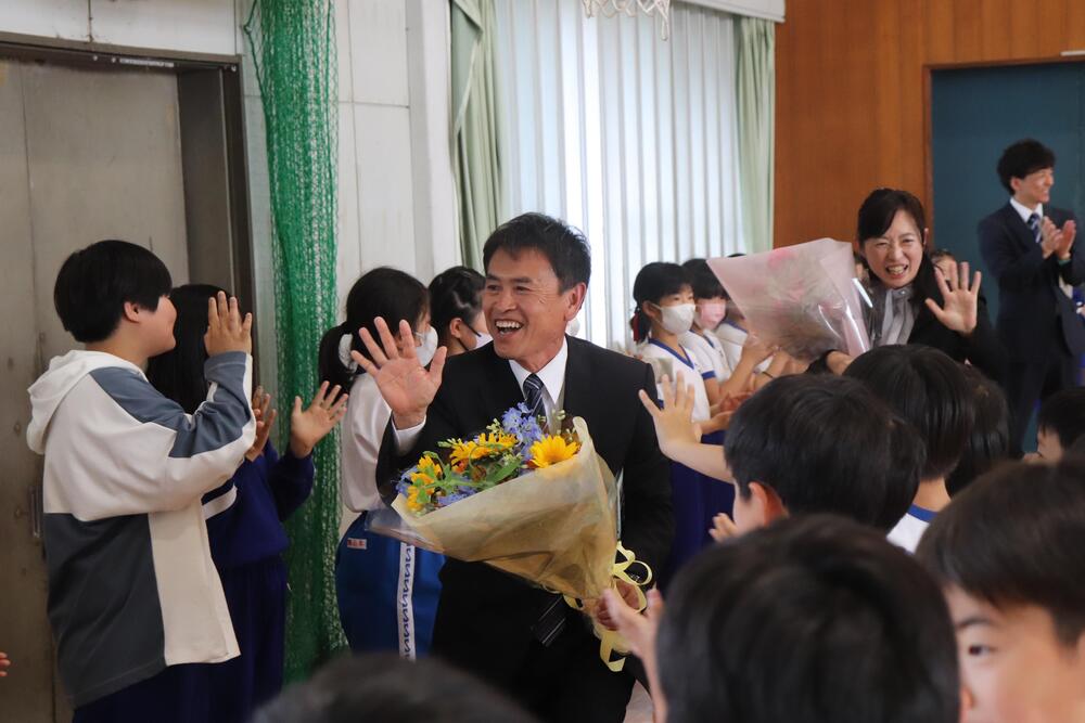 整列した生徒の間をハイタッチしながら見送られる山口先生と村松先生の写真