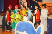 壇の前に集まって歌っている3年生の写真