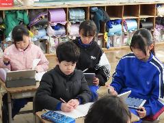 問題に取り組む低学年の子どもと、アドバイスを送る高学年の子ども