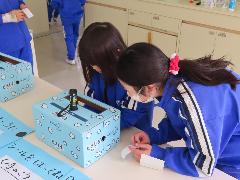 健康委員と一緒にブラックライトで手の汚れを確認する子ども