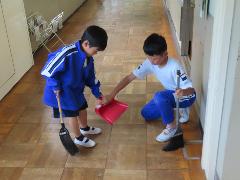 塵取りの使い方を教えながら掃除を進める子ども