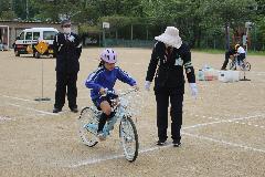 交通指導員さんにアドバイスをもらいながらコースを走る子ども
