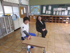 机の前で児童と大人の人が話している写真
