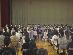 大人たちの座っている前に並んでいる子供たちの写真