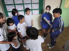 資料を見ながら話をする男の子の周りに集まって話を聞く子供たちの写真