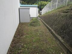 建物と石垣の間に物置倉庫が建っている写真