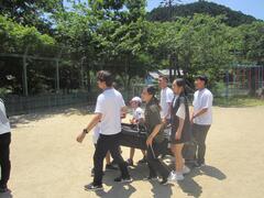 児童たちが黒いものを一緒に運んでいる写真