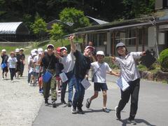 赤白帽子をかぶった子供たちが2列に並んで楽しそうに外を歩いている写真