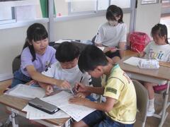 2人の児童に勉強を教えている児童の写真