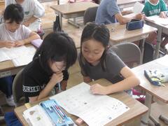 一つの机で2人の児童が勉強をしている写真