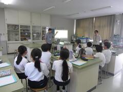 理科室で大人の話を聞く子供たちの写真
