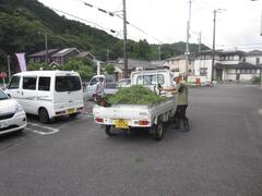 荷台に草木を載せた軽トラックの後ろ姿の写真
