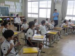 黄色いノートの置かれた席に着く子供たちの写真