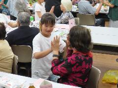 お年寄りと手遊びをする子ども