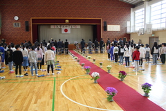 体育館にまっすぐに敷かれたレッドカーペットの両脇に並ぶ子供たちの写真